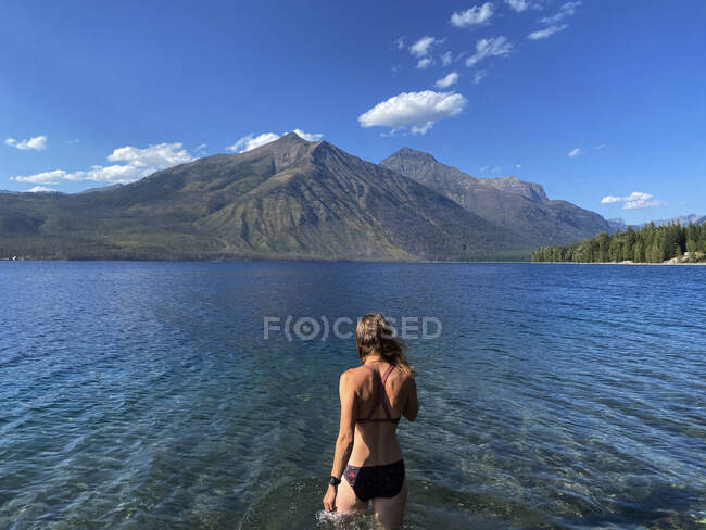 Uma mulher entra no Lago McDonald no Parque Nacional Glacier, MT. — Fotografia de Stock