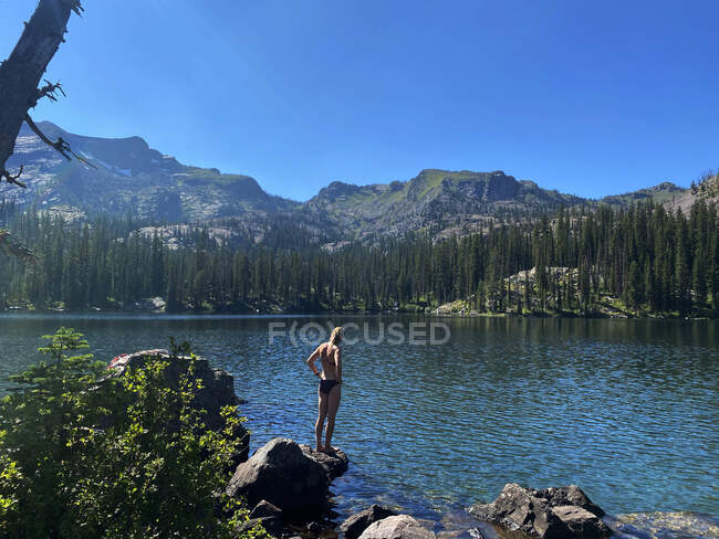 Una joven se prepara para saltar a un lago alpino en Montana. - foto de stock