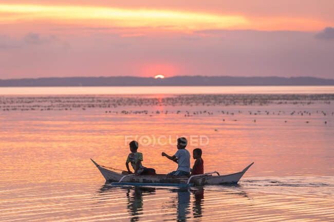 Enfants dans un bateau pendant le coucher du soleil — Photo de stock