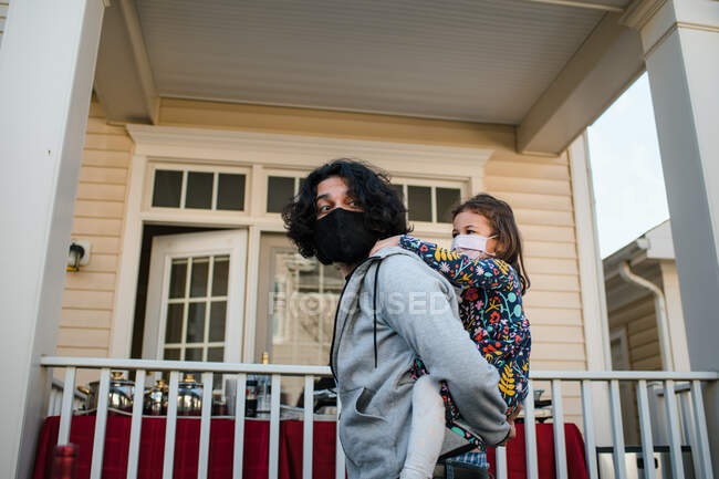 Dad giving daughter piggy back ride both wearing masks — Stock Photo
