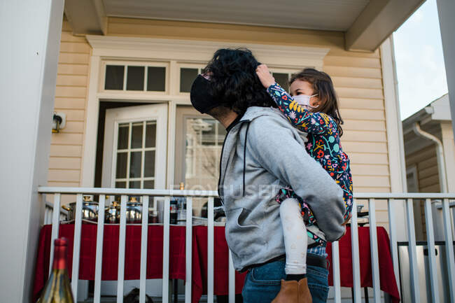 Маленькая девочка тянет папу за волосы во время поездки на спине в масках — стоковое фото