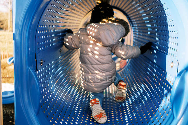 Kleines Kleinkind in Winterkleidung im Spielplatztunnel — Stockfoto
