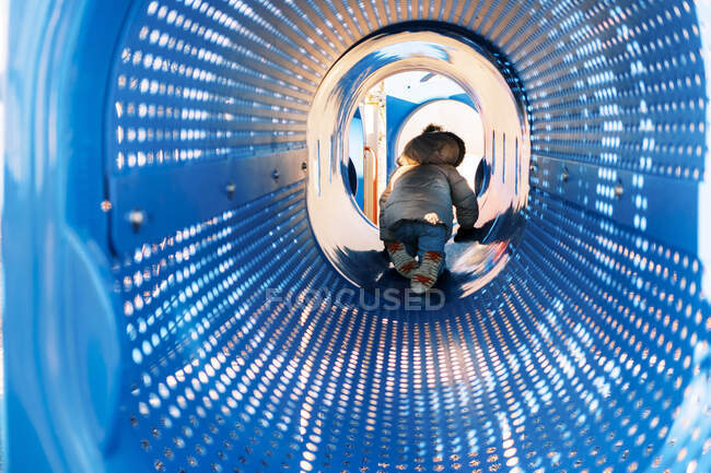 Little toddler girl crawling through tunnel at playground — Stock Photo