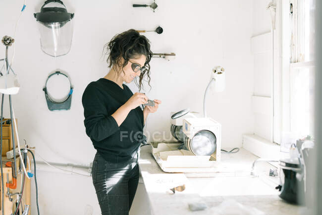 Женщина-ювелир улыбается с удовлетворением, работая в домашней студии — стоковое фото