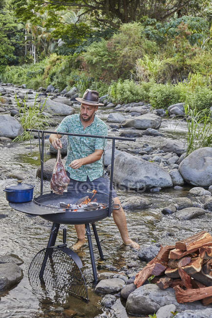 Koch kocht über offenem Feuer auf Campingplatz in der Nähe von Bachbett — Stockfoto