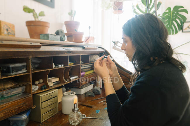 Female jewler focusing on creating small piece at home studio space — Stock Photo