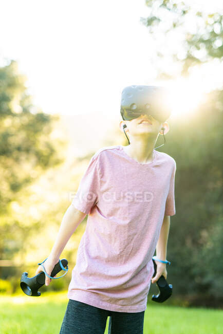 Tween having virtual experience with VR goggles outside in green field — Stock Photo