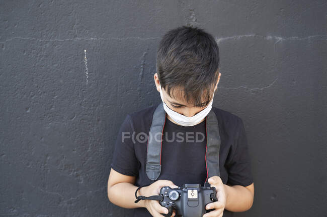 Niño pequeño con su cámara fotográfica usando una máscara - foto de stock