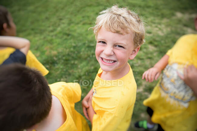 Glücklicher blonder Junge lächelt in die Kamera, während er draußen in der Schlange steht — Stockfoto