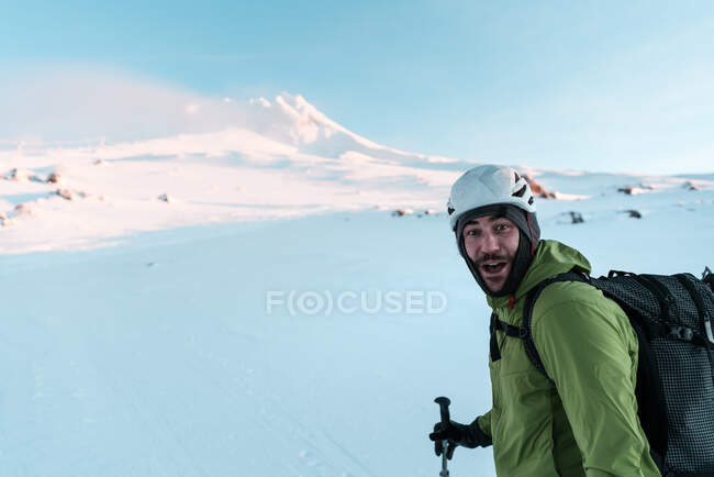 Лыжник смотрит в камеру и улыбается, поднимаясь на гору. — стоковое фото