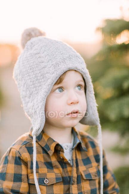 Niño vistiendo sombrero de invierno busca mágico, vacaciones, reflexivo - foto de stock