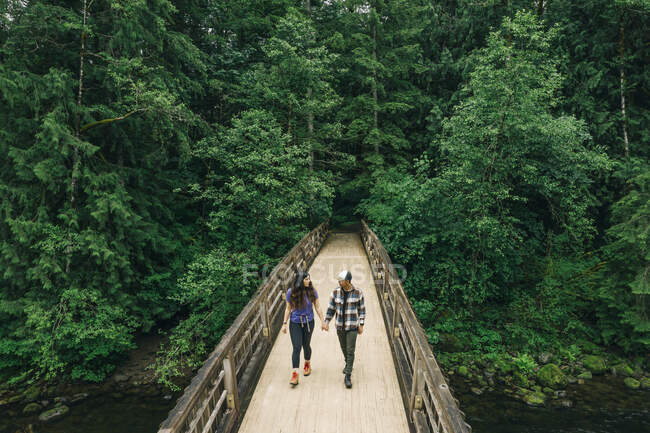 Una joven pareja disfruta de una caminata en un bosque en el noroeste del Pacífico - foto de stock