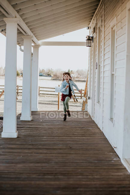 Happy young girl running on deck of patio outside — Stock Photo