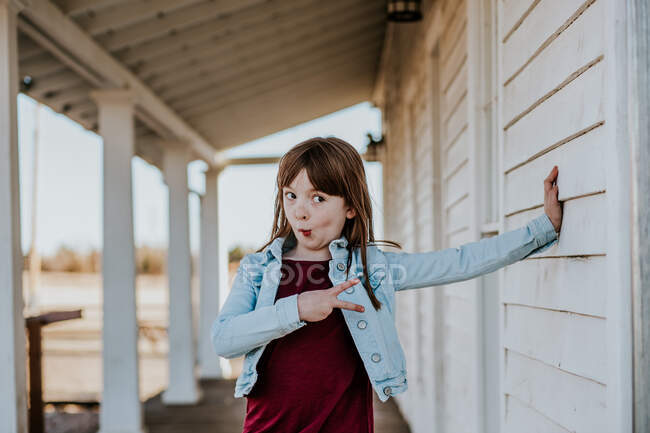 Silly young girl making a funny face and giving peace sign — Stock Photo
