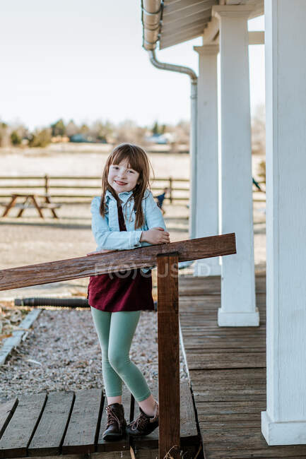 Щаслива молода дівчина стоїть на патіо посміхається в сонячний день — стокове фото
