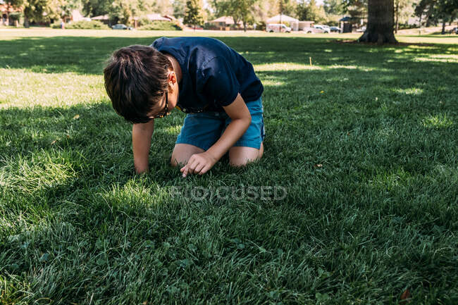 Мальчик играет на траве в парке в теплый день — стоковое фото