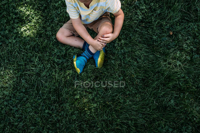 Мальчик, сидящий в траве в солнечный день — стоковое фото