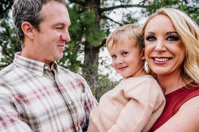 Retrato de una familia feliz fuera de los árboles - foto de stock