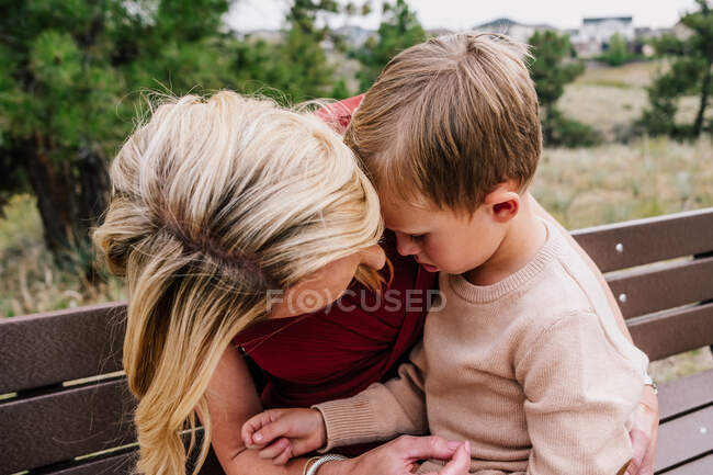 Mãe segurando e reconfortante jovem filho lá fora — Fotografia de Stock