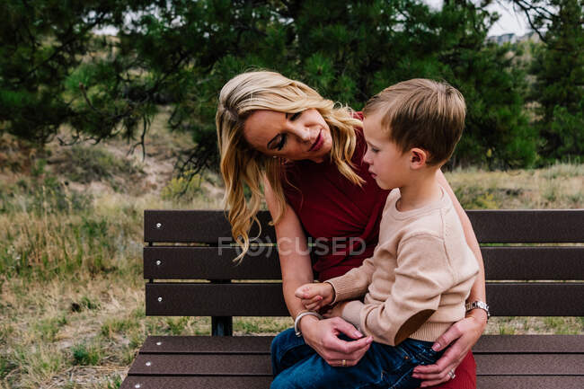 Mãe e filho jovem sentados em um banco falando — Fotografia de Stock