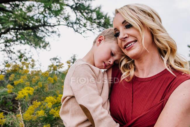 Mãe segurando e reconfortante jovem filho lá fora — Fotografia de Stock