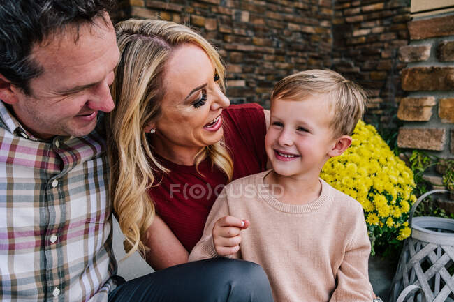 Familia feliz sentada en el porche sonriendo y riendo - foto de stock