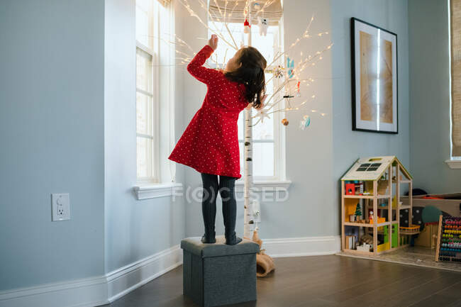 Kleines Mädchen hängt Weihnachtsschmuck an modernen Birken-Weihnachtsbaum — Stockfoto
