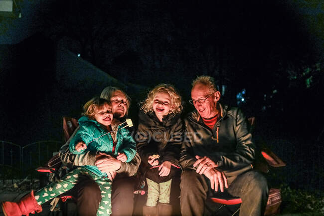 Grandparents and grandchildren laughing together roasting marshmallows — Stock Photo