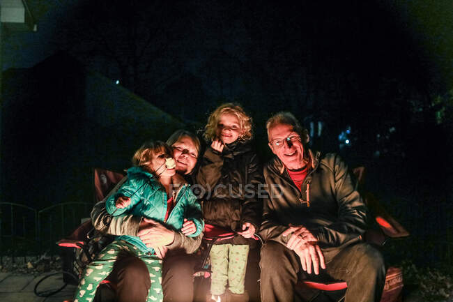 Grands-parents et petits-enfants ensemble regardant la caméra avec une lueur de feu — Photo de stock