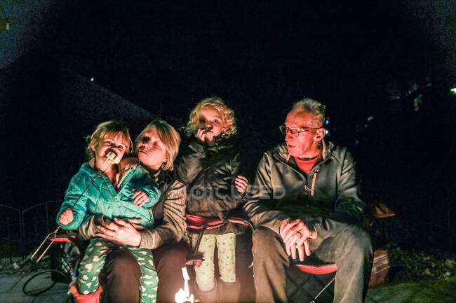 Бабусі і дідусі сидять з онуками навколо кабіни вогню — стокове фото