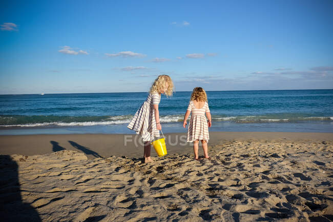 Deux filles jouant près de l'océan avec un ciel bleu dans des tenues assorties — Photo de stock
