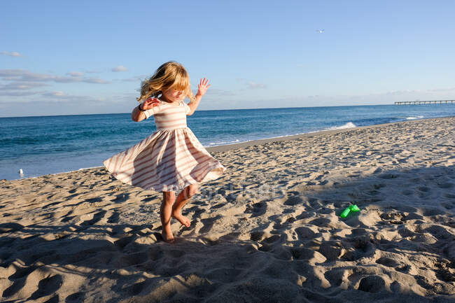 Маленькая девочка танцует на пляже с голубым небом — стоковое фото
