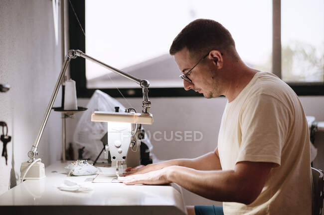 Homem de 35 anos usando a máquina de costura em casa. Jovem costura — Fotografia de Stock
