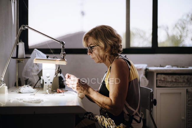 Mujer usando máquina de coser para hacer máscara médica - foto de stock