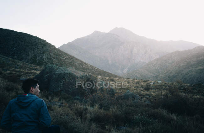 Joven sentado en la montaña. en Mendoza Argentina - foto de stock
