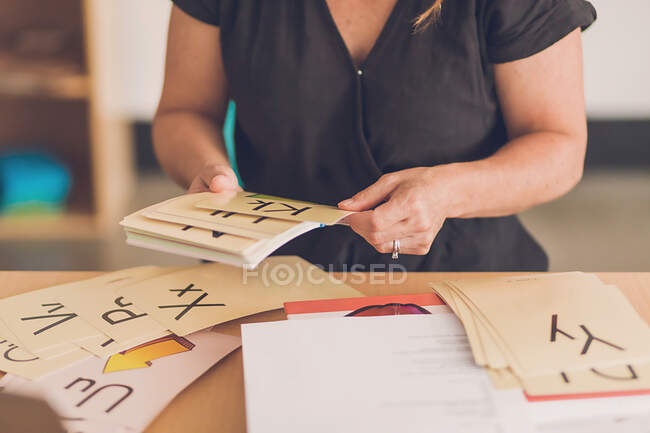 Female teacher sorting out alphabet picture cards in her classroom. — Stock Photo