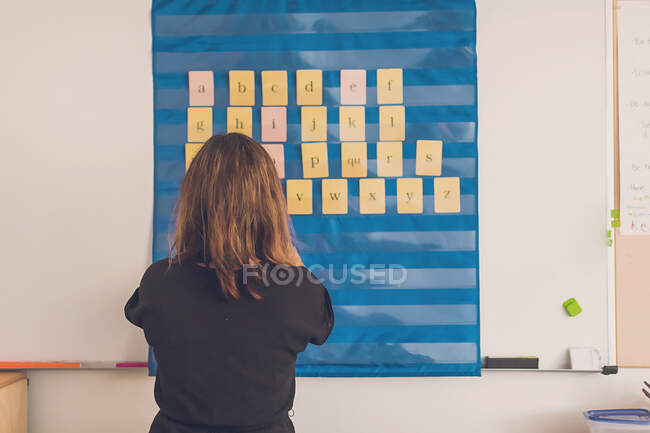 Profesora organizando cartas en su tablero en su aula. - foto de stock