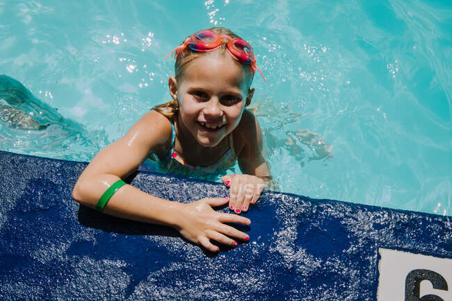 Little Girl holding onto side of the pool looking up and smiling — love,  united - Stock Photo | #441714840