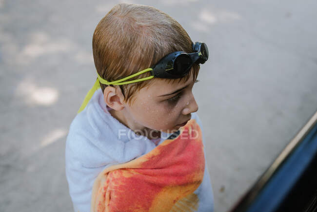 Boy wrapped in towel with goggles on his head and wet hair — Stock Photo