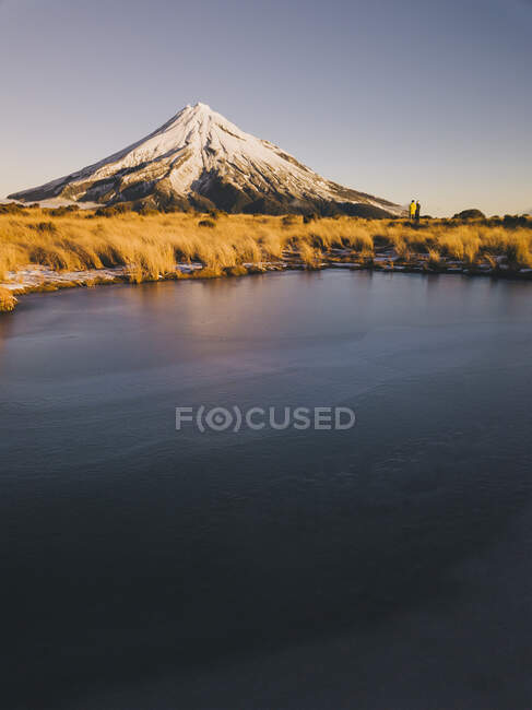 Young couple in the distance enjoying sunset time at Mt Taranaki, New Zealand — Stock Photo