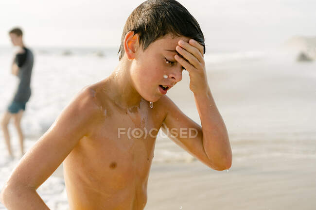 Child wiping water off  his face at the beach in New England — Stock Photo