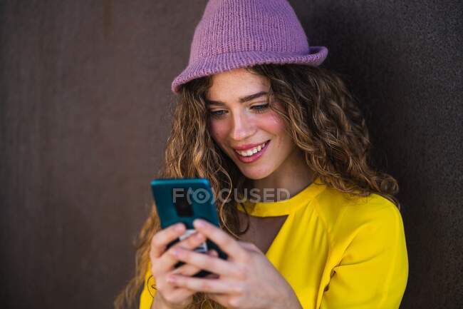 Весела молода жінка використовує смартфон на вулиці — стокове фото