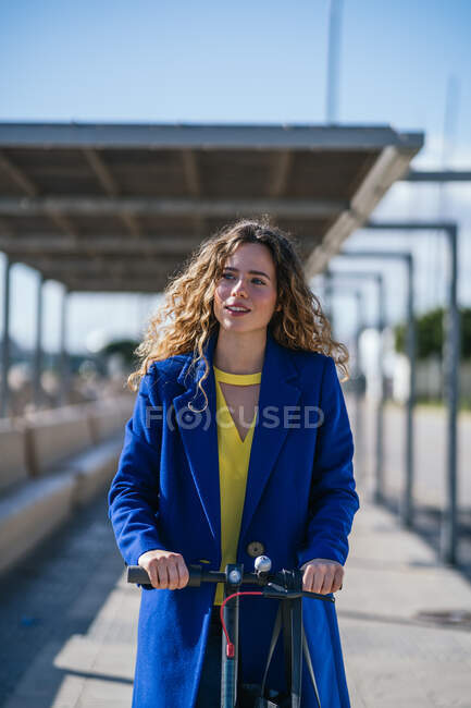 Молода жінка верхи на електричному скутері в місті — стокове фото