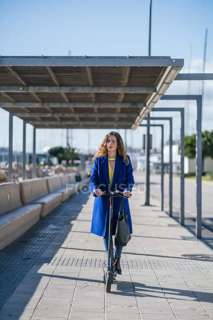 Молодая женщина на электрическом скутере в городе — стоковое фото