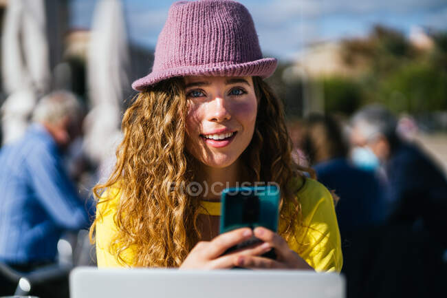 Stilvolle Frau mit Smartphone und Laptop in Cafeteria — Stockfoto