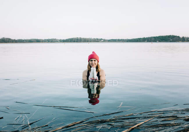 Femme en chapeau rouge nageant dans le lac — Photo de stock
