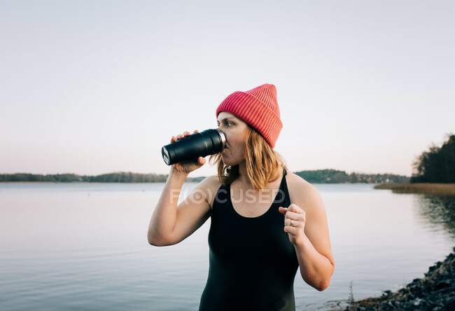Nordische Frau trinkt Heißgetränk nach Kaltwasserschwimmen im Meer — Stockfoto