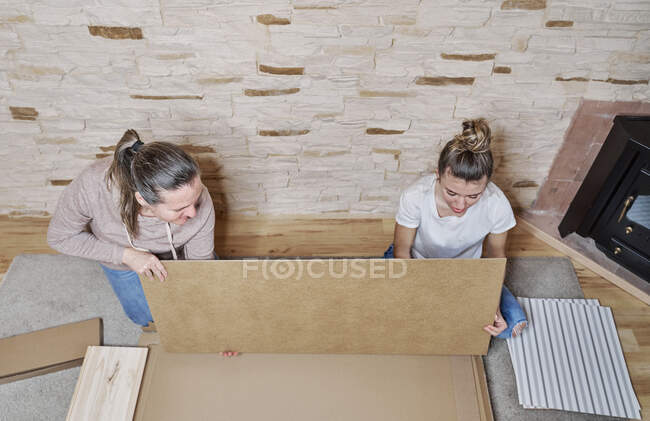 Vue de deux femmes obtenant un morceau de bois ou une étagère d'un papier — Photo de stock