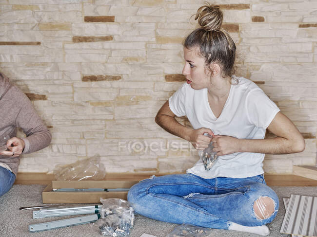Vorderseite eines kaukasischen Mädchens, das eine Plastiktüte mit Schrauben öffnet — Stockfoto