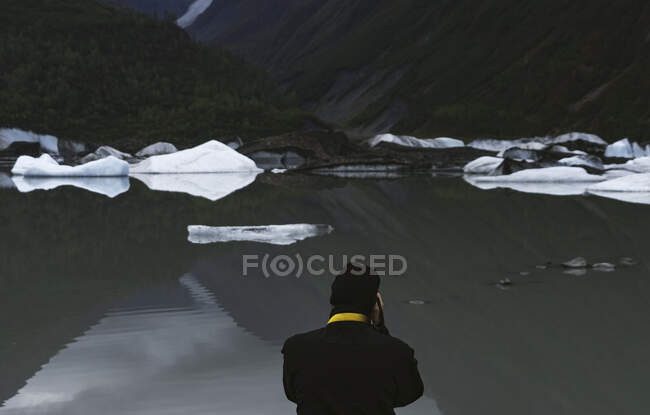 A man takes photos of glacier ice at a lake in Alaska — Stock Photo